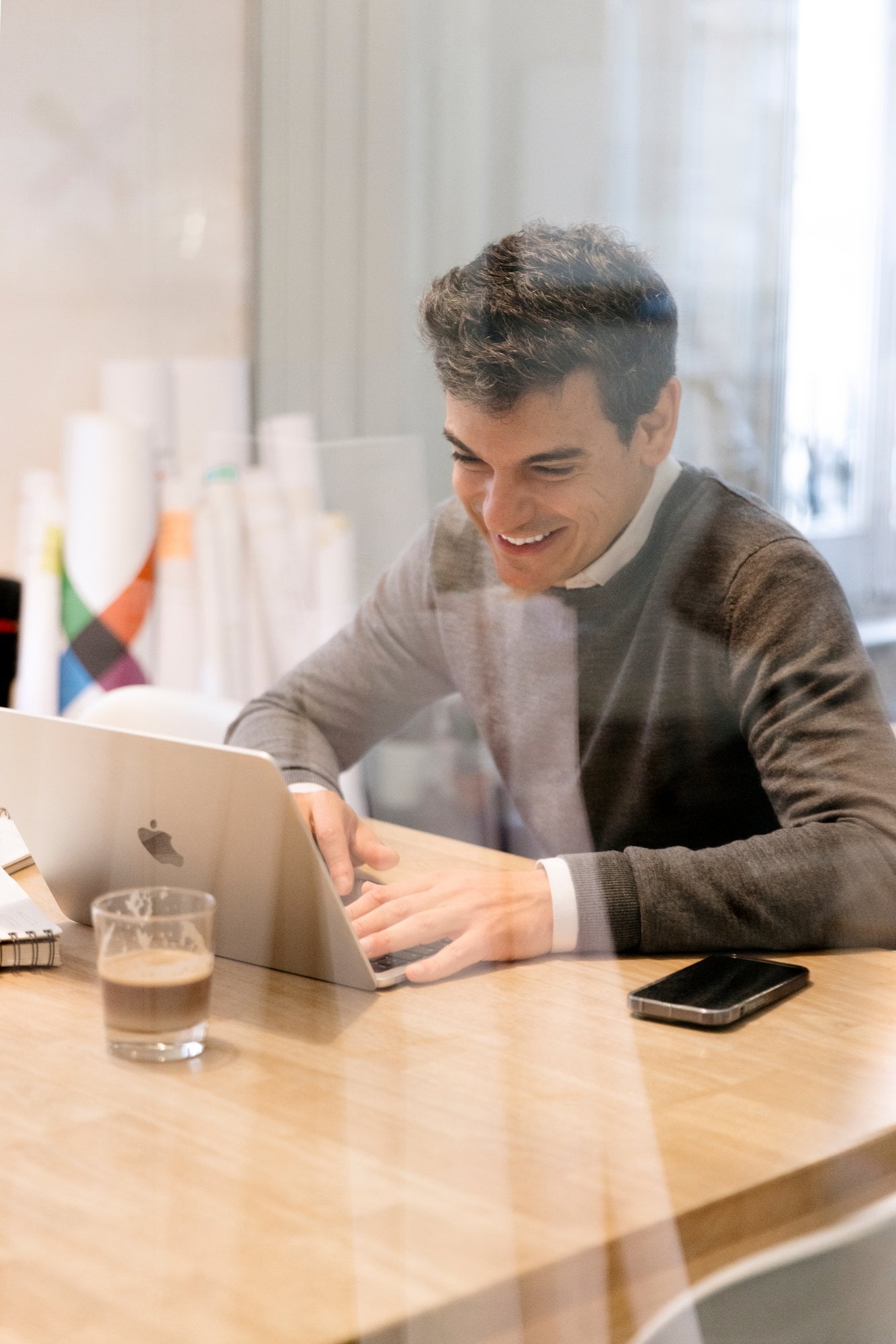 Hombre sonriente trabajando con su portátil en una mesa de madera