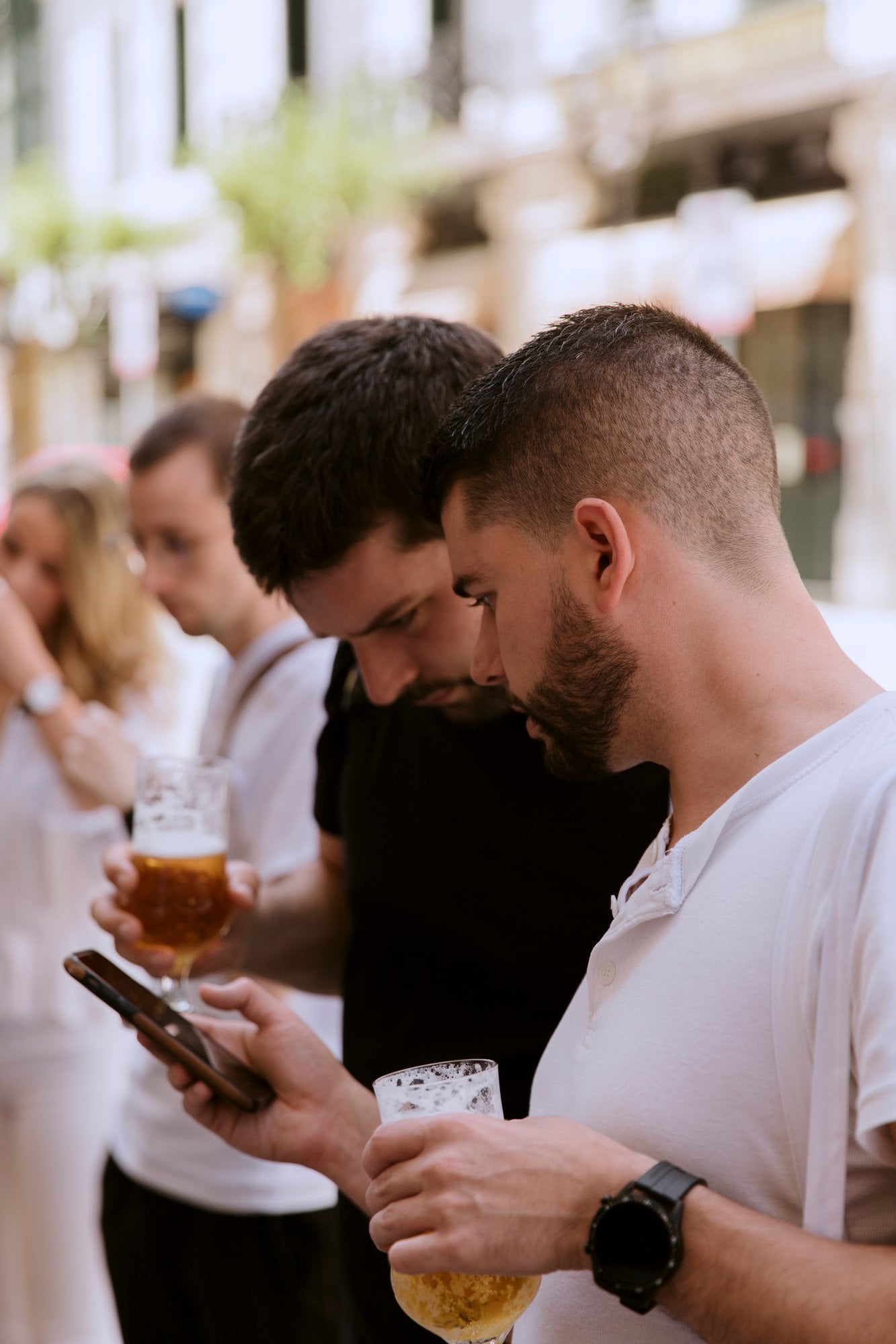 Compañeros con cervezas mirando un móvil en un afterwork