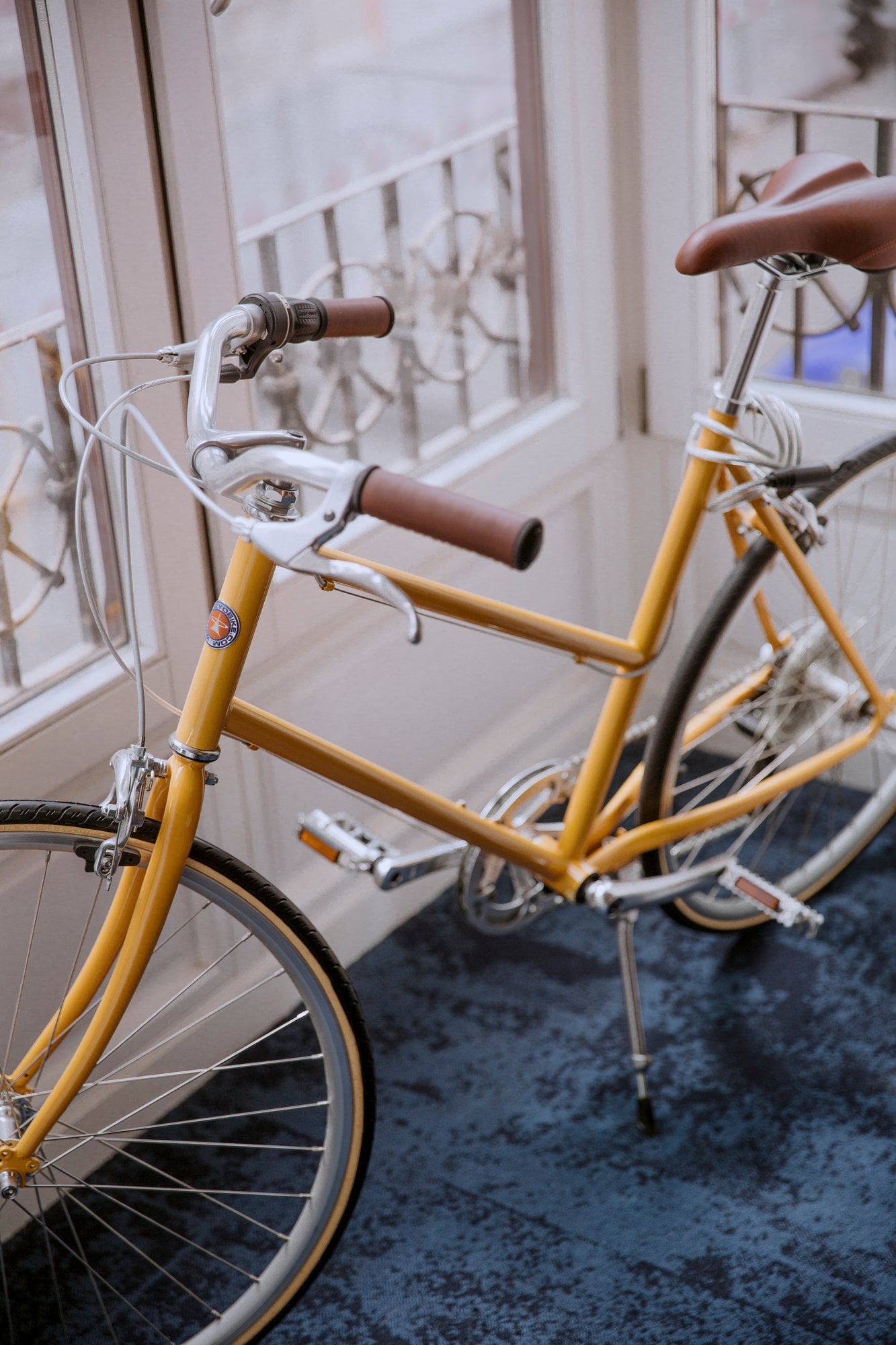 Bicicleta amarilla aparcada dentro del estudio junto a la ventana