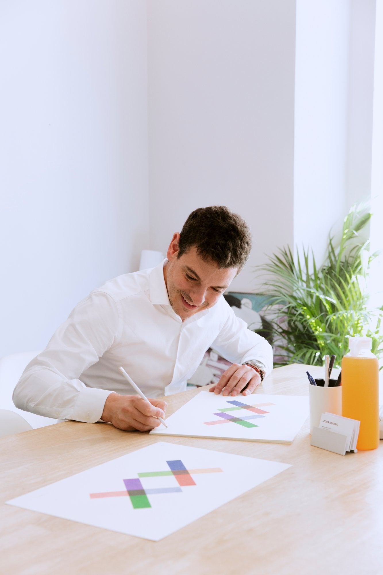 Hombre sonriente dibujando el logotipo del estudio sobre papel