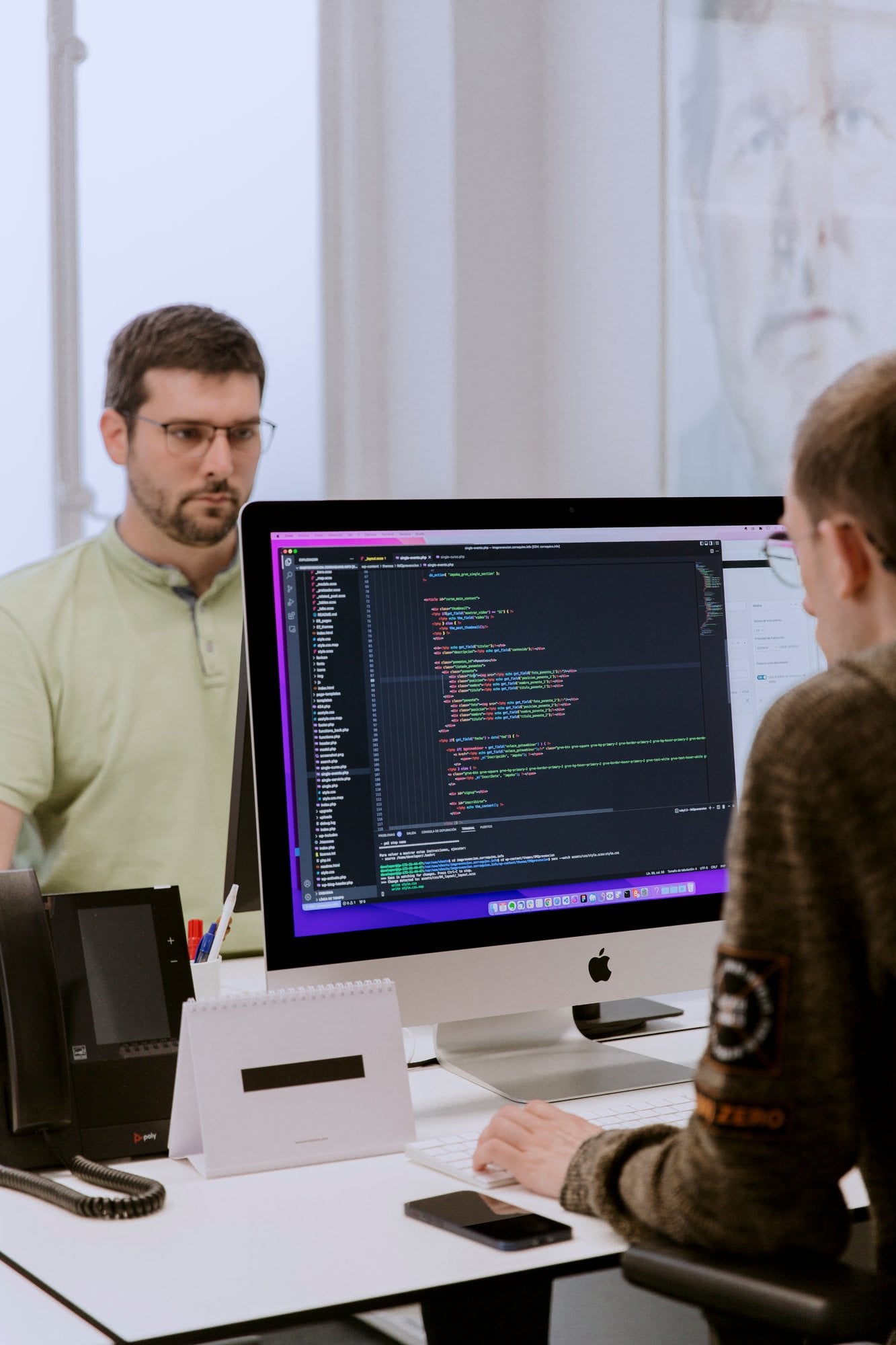 Dos desarrolladores revisando código juntos en un iMac