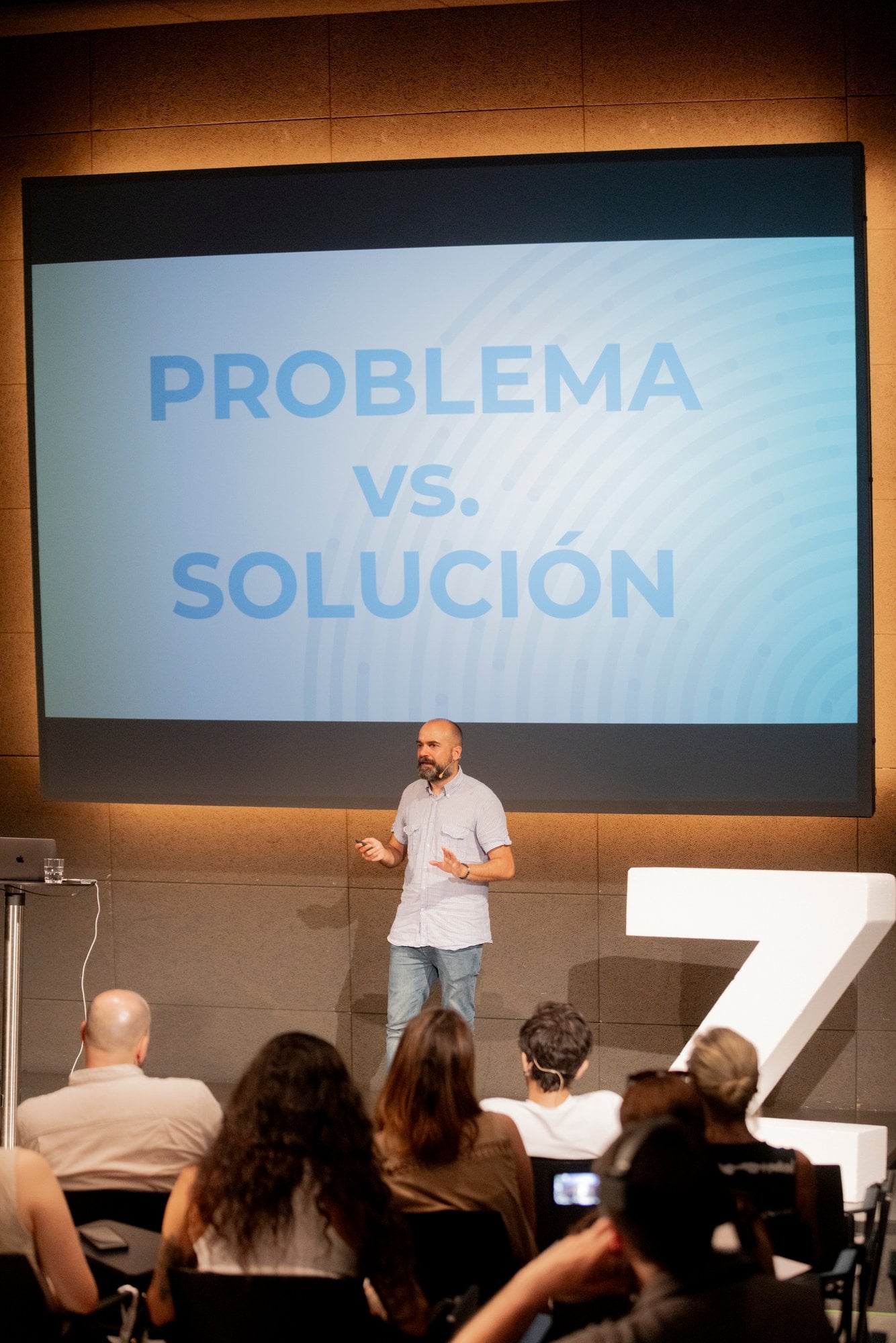 Ponente ante la diapositiva «Problema vs. solución», junto a una gran Z